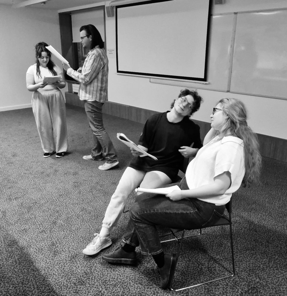 Four actors, 2 stood and 2 sitting rehearsing for a play
