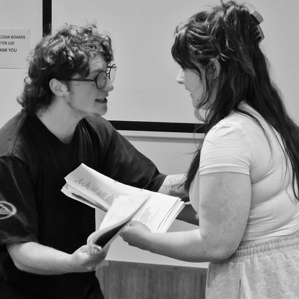 2 actors facing each other close together as they rehearse