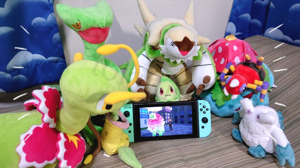 Nintendo Switchの画面に映るメガメガニウムを見つめる、ぬいぐるみのメガニウム、ウツボット、ジュカイン、チコリータ、ブリガロン、フシギバナ、アリアドス、ユキノオー