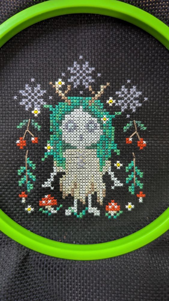A cross stitched mavka on black fabric