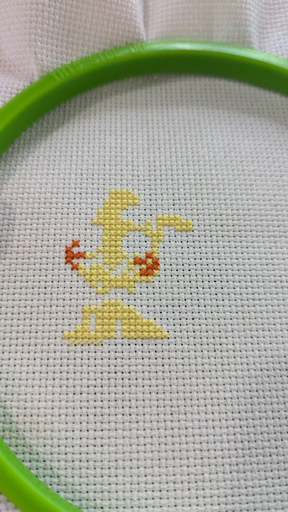 A mysterious Pokemon cross stitched onto white fabric, clearly not finished. 