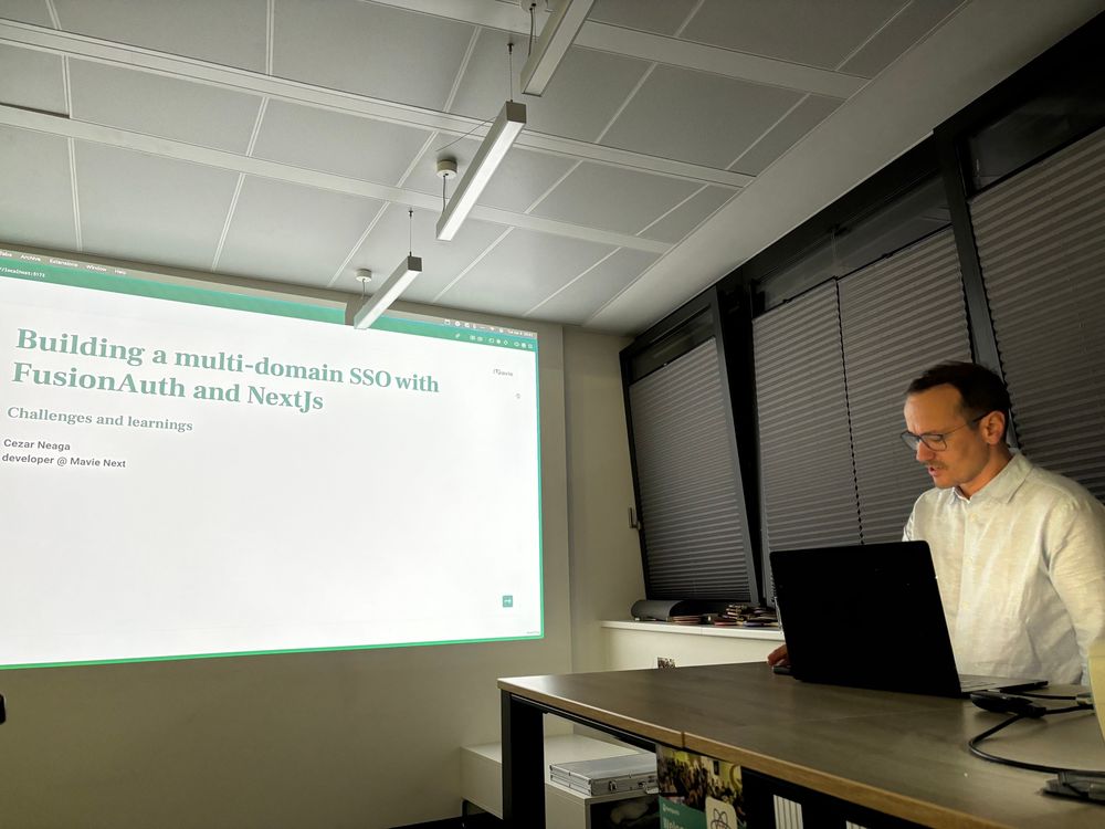 Cezar on Stage, with a slide showing the talk title in the background 