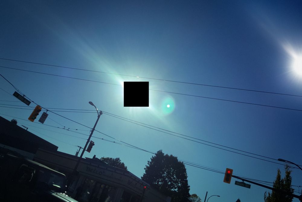 A picture of a suburban street in a clear sunny day, pointing towards the sky. The sun sits to the right of the image. There is nothing in the middle.