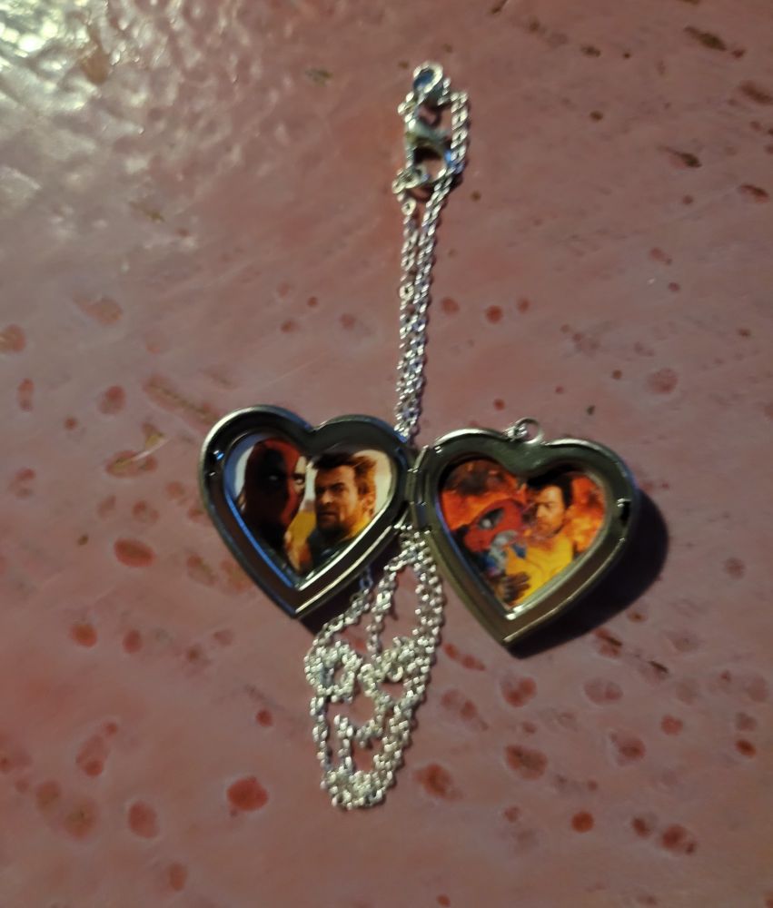 a silver locket, inside are two photos of deadpool and wolverine holding each other (from the movie deadpool & wolverine)
