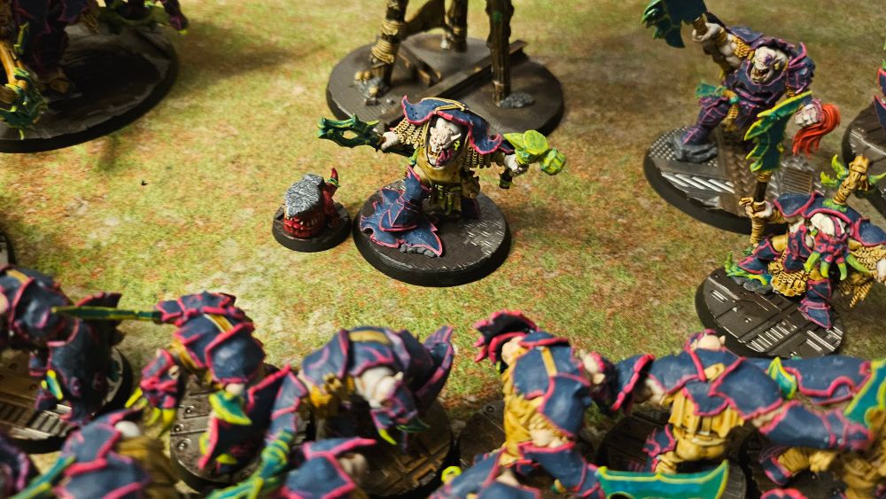 A photo of my ironjawz army with mostly blue armour trimmed with neon pink and green weaponry with neon yellow edges. This one focused on zoggrok anvilsmasha and his squig klonk