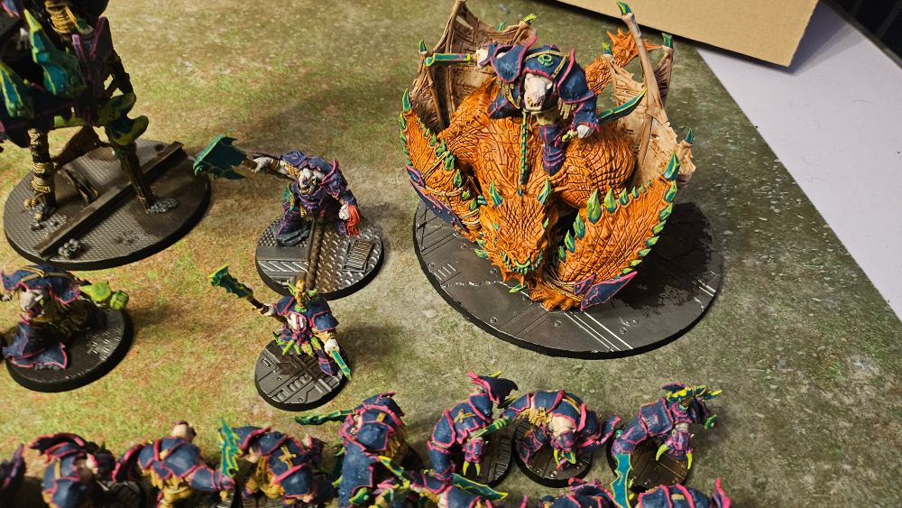 A photo of my ironjawz army with mostly blue armour trimmed with neon pink and green weaponry with neon yellow edges. This one focused on a orange coloured mawkrusha and a couple heros