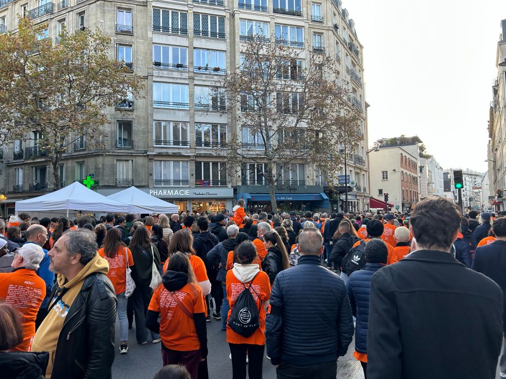 foule de dos en t-shirt orange devant le café belle équipe. 
