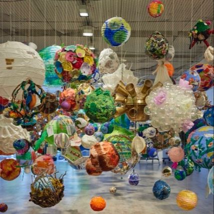 A vibrant and colorful installation of 400 handmade spheres, each uniquely crafted from various materials such as paper, fabric, and plastic.