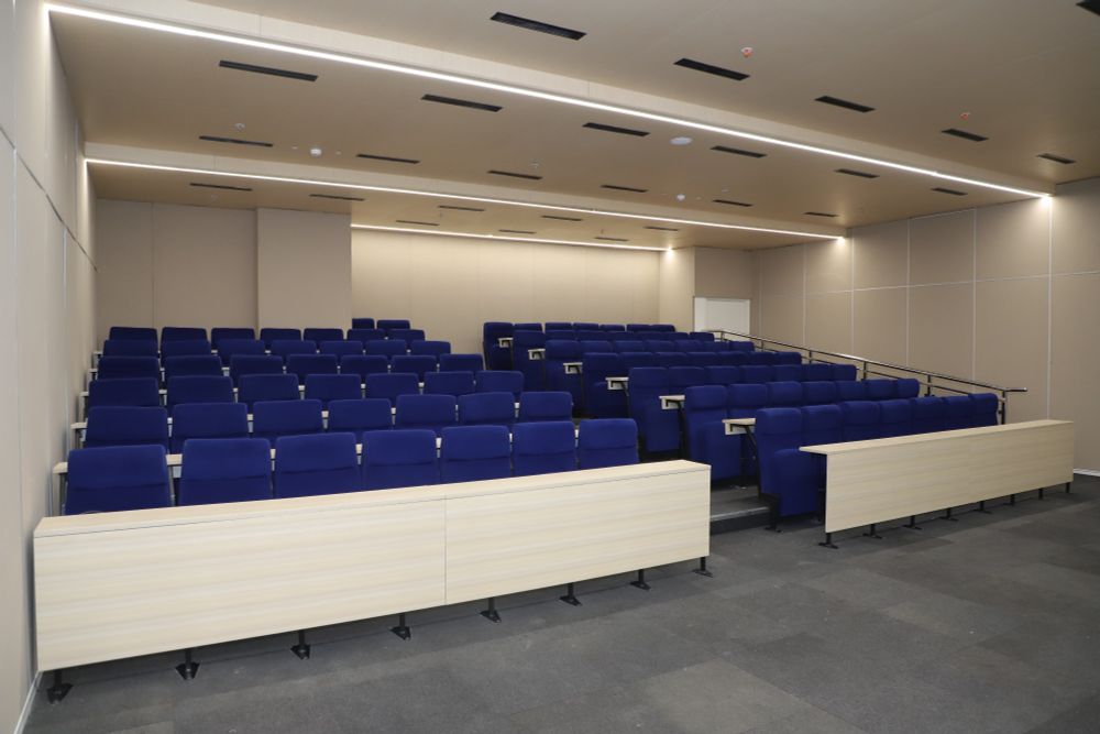 An empty lecture hall at University of Southampton Delhi with tiered rows of blue upholstered seats. 