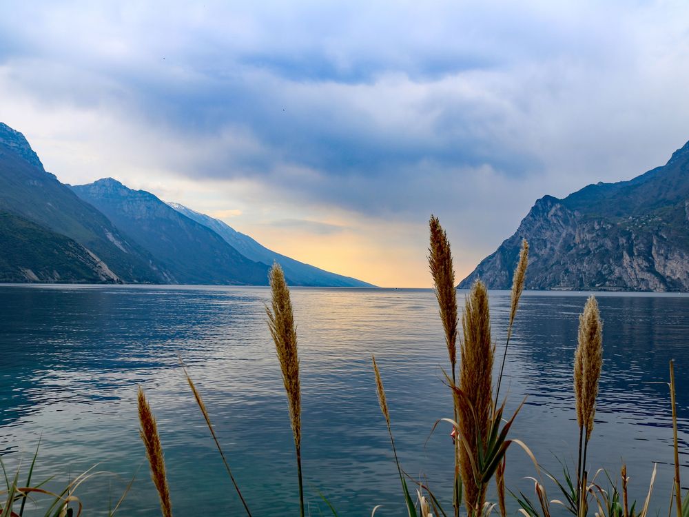 Blick auf einen See, links und rechts sind höhere Berge zu sehen. Im Vordergrund sieht man ein wenig Uferbegrünung.