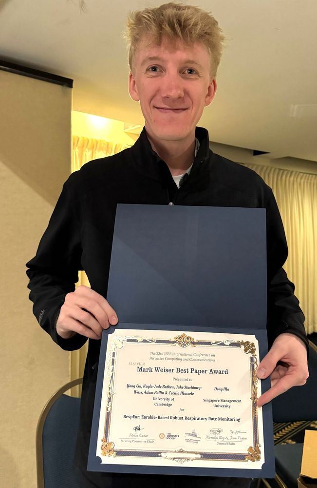 Researcher Jake Stuchbury-Wass holds the Mark Weiser Best Paper Award, given at IEEE PerCom 2025, the International Conference on Pervasive Computing and Communications. Jake and colleagues won for their work in repurposing the in-ear microphones in our earbuds for collecting and analysing our breathing rates (a key vital sign), demonstrating a new way for us to monitor our health.