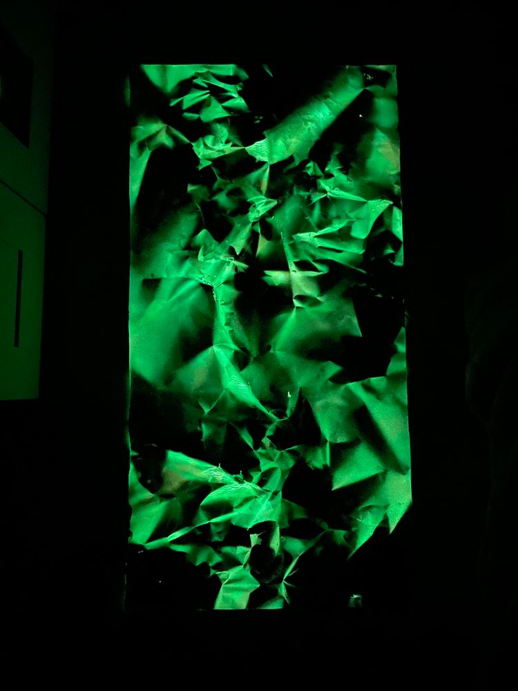 Obra “Dragontinas: Rubí” brillando en la oscuridad con tonos verdes fosforescentes. Los pliegues del vinilo crean un relieve que recuerda a rocas y grietas iluminadas, como si la energía interior de la pieza siguiera viva incluso sin luz externa.
