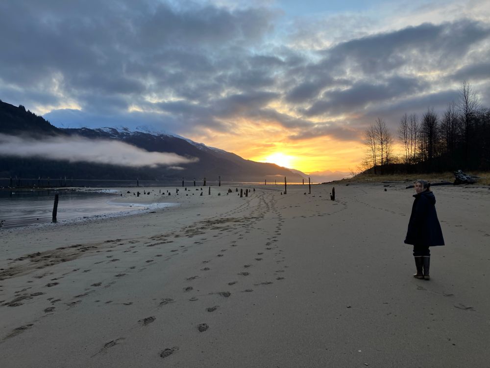 Sunrise on the beach with woman walking
