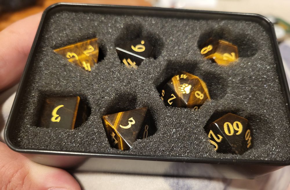 A set of 7 tigers eye dice. The d20 has a bear paw on the 20 face