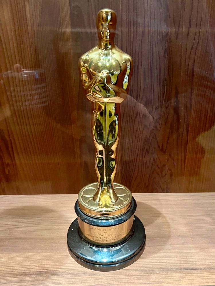 An Academy Award (Oscar) statue, gold in color, displayed on a wooden surface. The engraved plaque at the base reads: "Academy Award to Wall-E for Animated Feature Film, Andrew Stanton."
