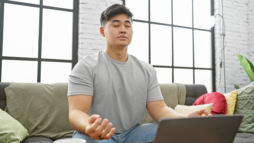 Young person meditating by a computer. 
