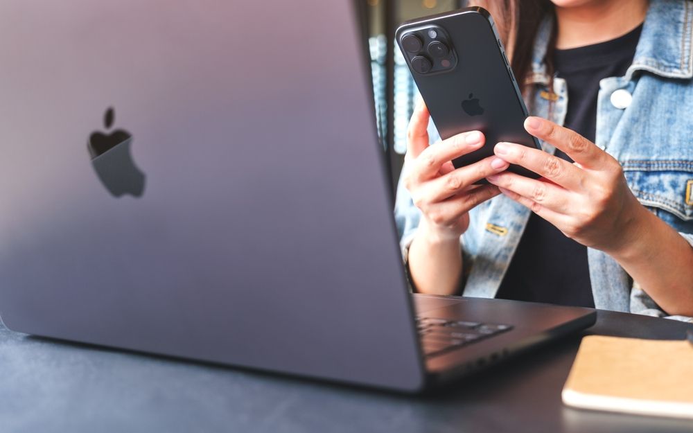 A woman looking at both laptop and phone. Stock photo. 