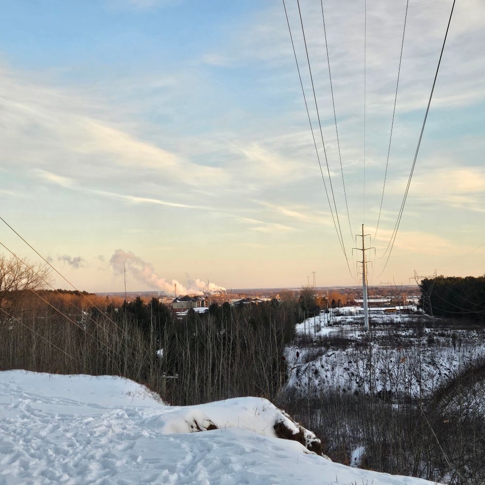 Vue enneigée, soleil couchant vers Trois-Rivières. Au loon, des fumées d'usine et à droite, des lignes haute tension d'hydroquébec