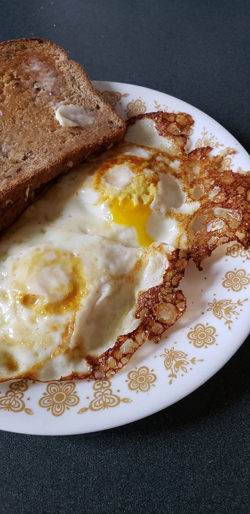 Plate with two eggs friend in olive oil and buttered toast