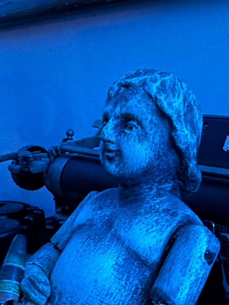 Deep blue lighting with carved wooden male doll looking Erie