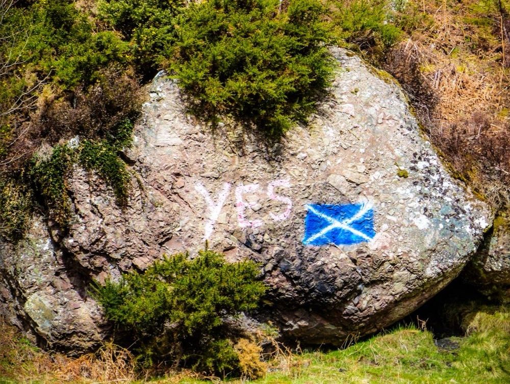 Rock in the countryside with a Scottish Saltire and the word YES painted on it 