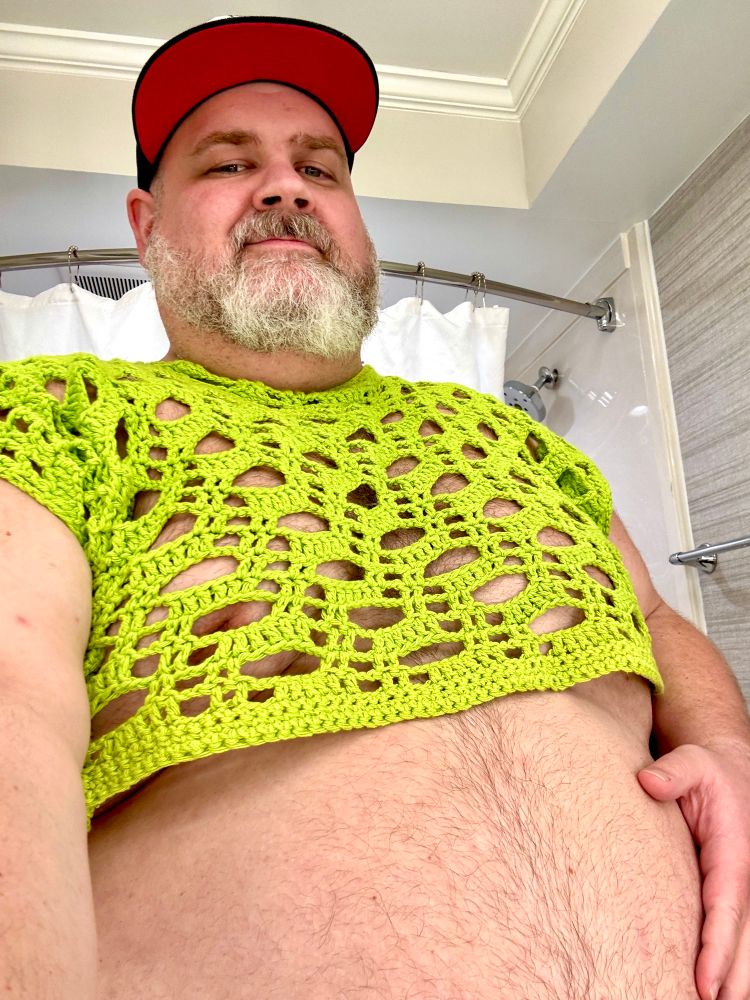 A photo of me in a neon green crocheted crop top holding my belly