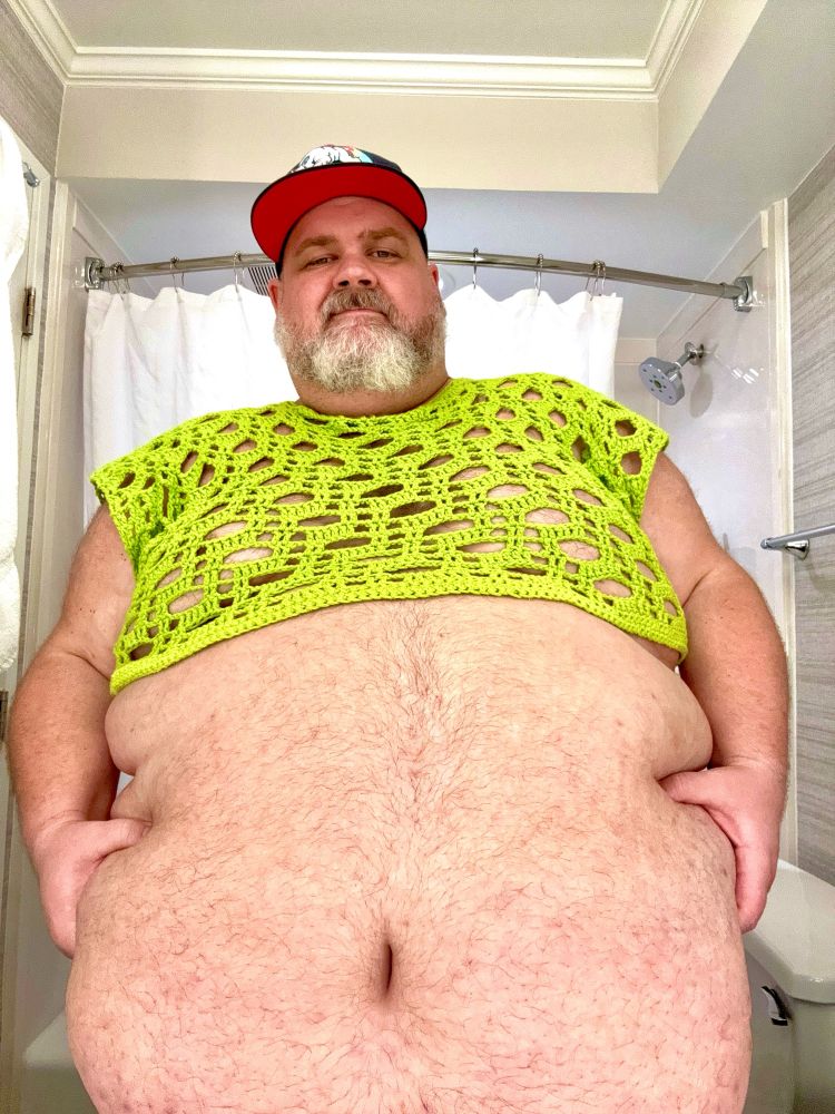 A photo of me in a neon green crocheted crop top holding my belly