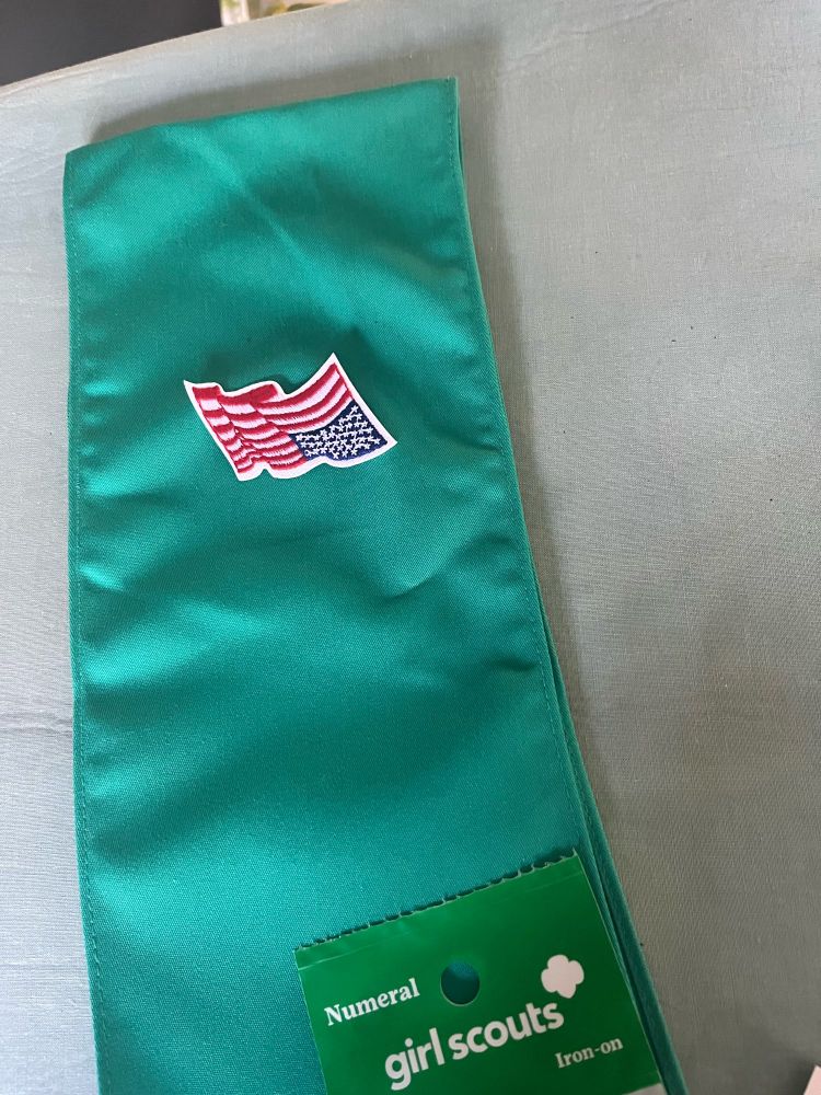 Green Girl Scout sash with upside down US flag.