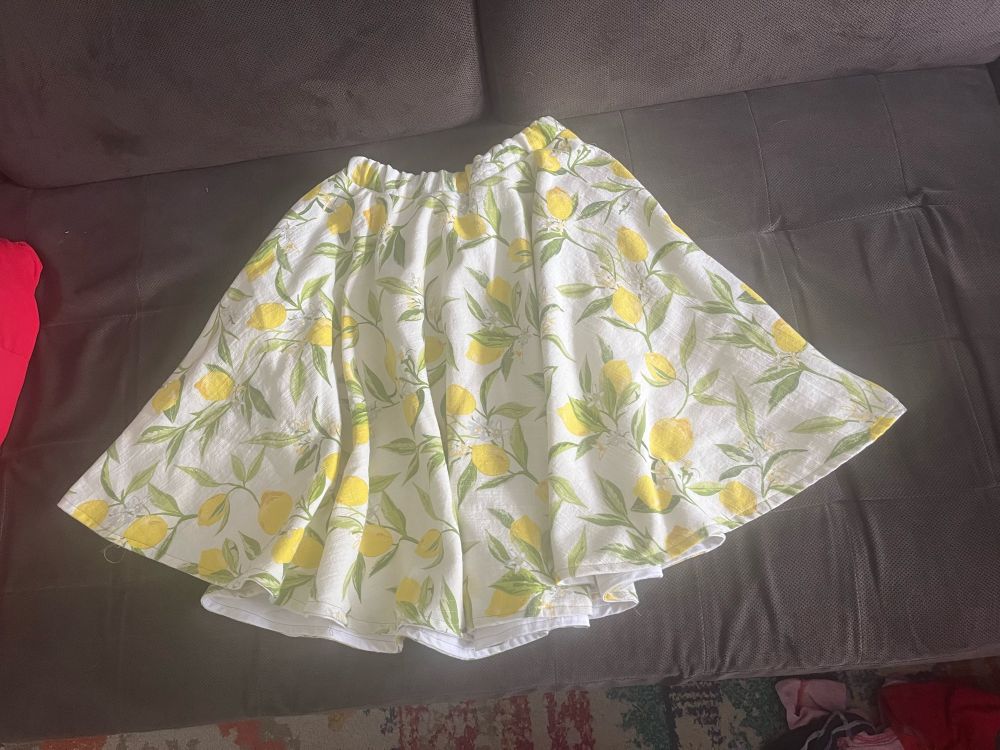 A white circle skirt with a lemon pattern on a gray background.