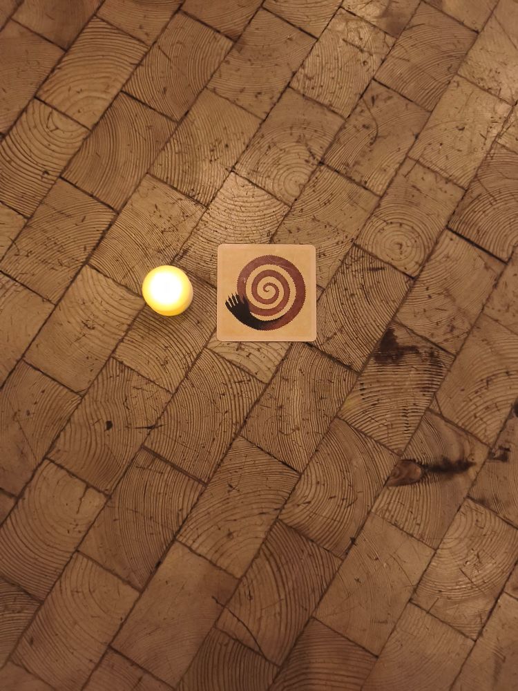 Eine Karte aus dem Spiel Werwölfe auf einem Paketfußboden neben einem LED Teelicht