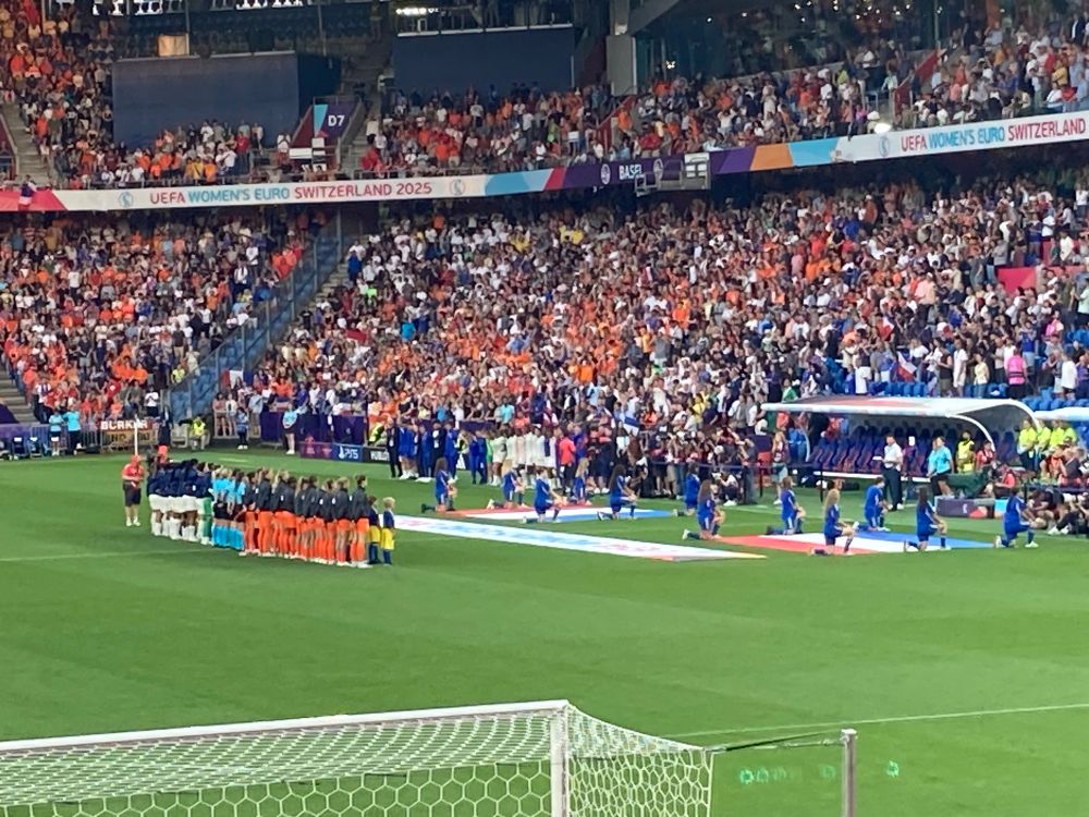 De teams staan voor de wedstrijd naast elkaar.