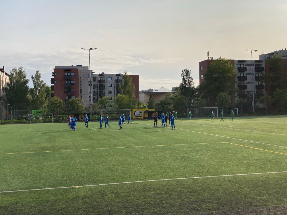 Een minuutje voor de wedstrijd. Op de achtergrond staan drie flats.