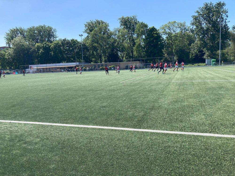 Een wedstrijdfoto aan de andere kant van het veld. In het gebouw zijn de kantine en kleedkamers gevestigd.