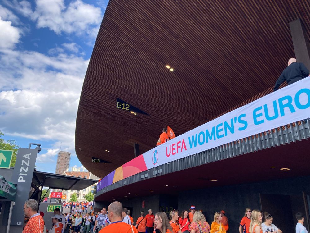 De buitenkant van het stadion. Rechts op de banner staat ‘UEFA WOMEN’S EURO’ en links is er een pizza verkooppunt.