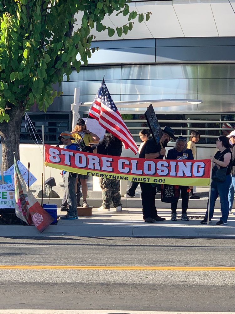 Protestors holding banner with the text: “STORE CLOSiING-Everything Must Go” in front of the just- opened Tesla Elon Musk diner in West Hollywood, CA