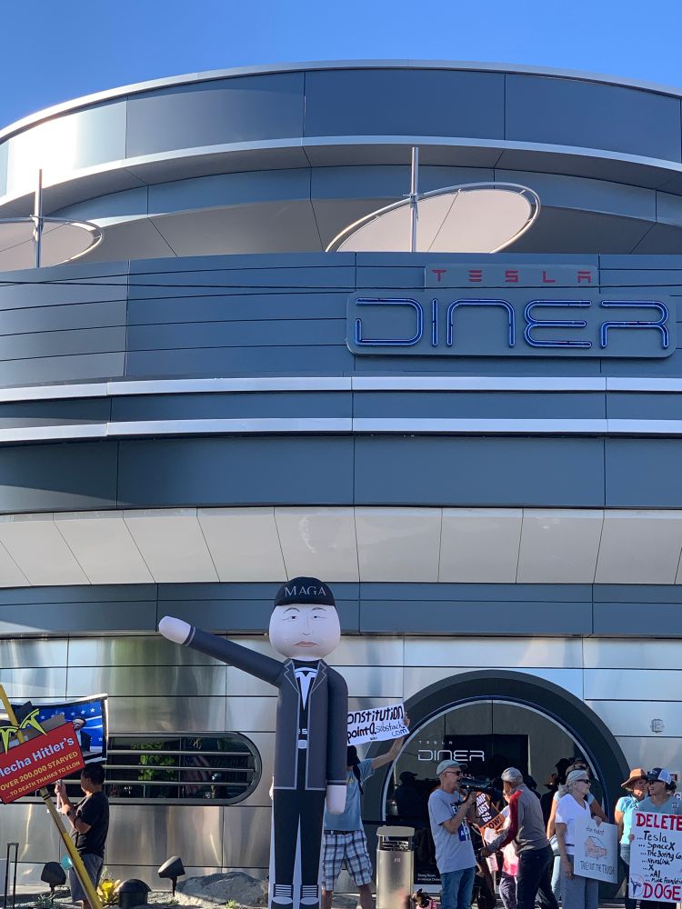 Photo of protest outside  Elon Musk’s newly-opened diner in West Hollywood including a 12-foot balloon in likeness of Ellon Musk flashing the Hitlerian “seig heil” sign.