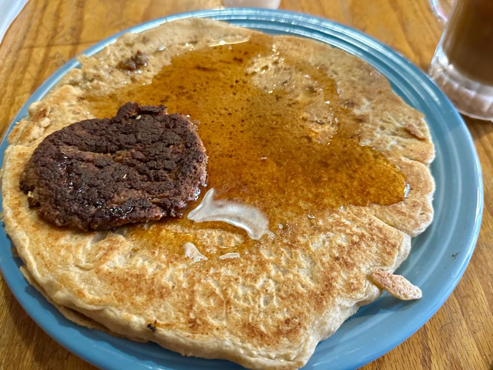 A blue dinner plate nearly completely covered by a single pancake