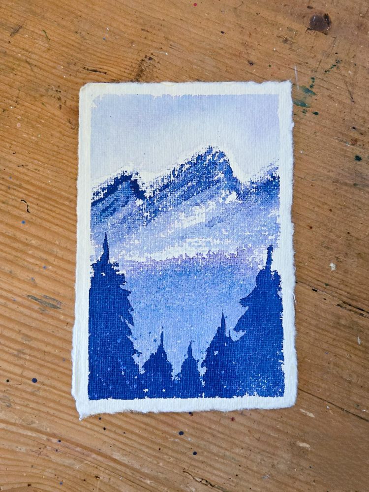A blueish-purple watercolor landscape with snowy mountains in the background, a lake in the midground, and pine trees in the foreground. The two trees on the left and right of the painting are tall, and the three trees in the middle are shorter, allowing a vantage point for the lake. 