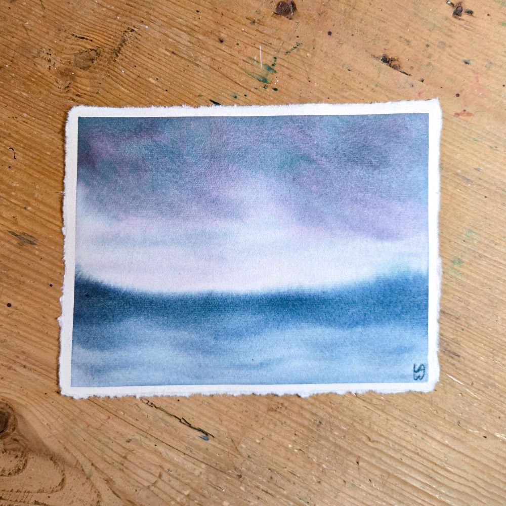 A watercolor painting of a lake with a storm off in the distance. The storm clouds are an interesting mix of turquoise and purple. The lake is a muted dark blue, darker near the horizon, and you can see swells in the water.
