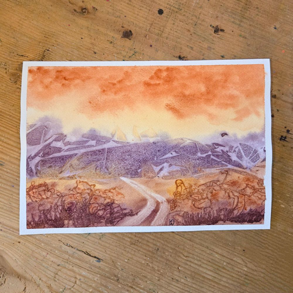 A watercolor painting of a somewhat abstract landscape. The sky is yellow with orange clouds, there are purple mountains in the background that have a rocky texture (from using plastic wrap on wet paint), and the foreground is a gradient yellow-orange-burgundy with plant-like textures (made from torn cheesecloth). There is a road that curves to the left and leads into the mountains. 
