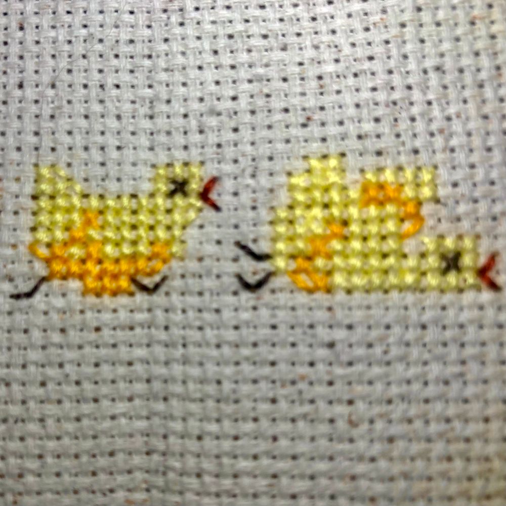 Small cross stitch of two yellow chicks, one is running, one has fallen over
