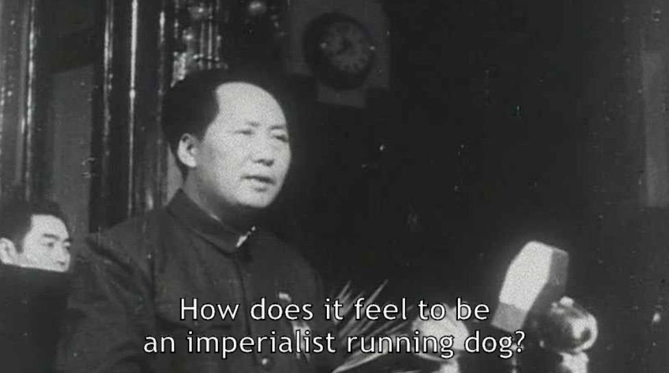 Foto em preto e branco de Mao Zedong em frente a microfones perguntando "How does it feel to be an imperialist running dog?"