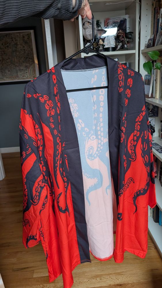 A haori type shirt, the top half is black with tentacles going down into the bottom red half, from the front 