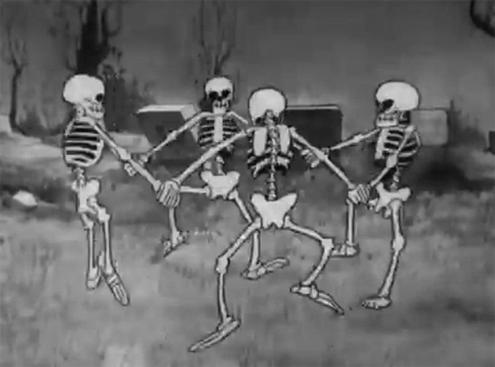 a group of skeletons are holding hands and dancing in a circle .