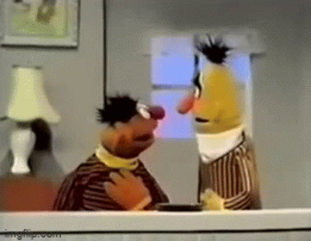 two sesame street characters are standing next to each other in a living room .