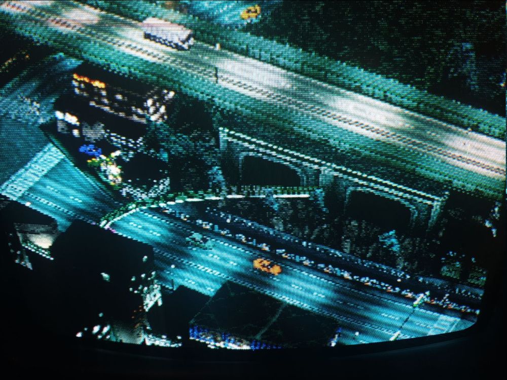 Looking up and across at an overpass an orange taxi cab drives by the lower road and a white truck can be seen on the overpass.