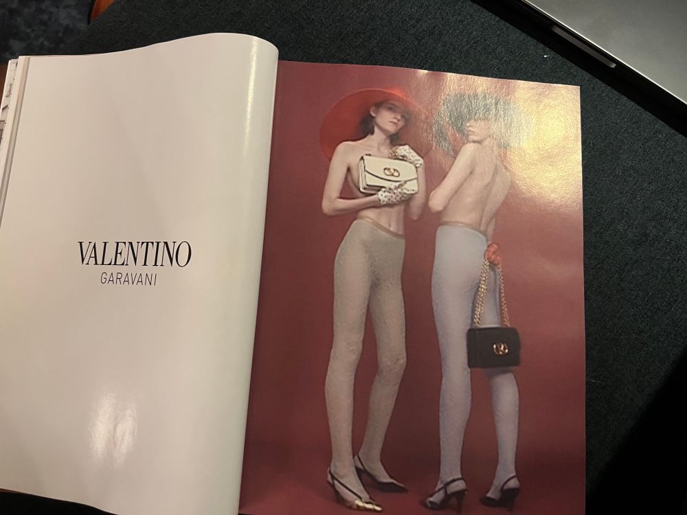 a Valentino ad showing two models wearing toghts and hars and wearing heel and carrying handbags. no clothes. the picture is out of focus