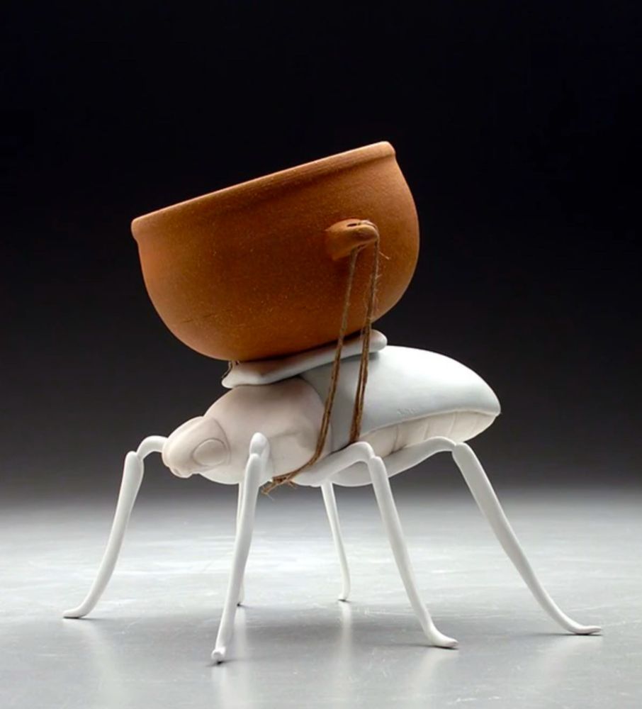 A white porcelain beetle with an earthenware bowl strapped to its back with twine. 