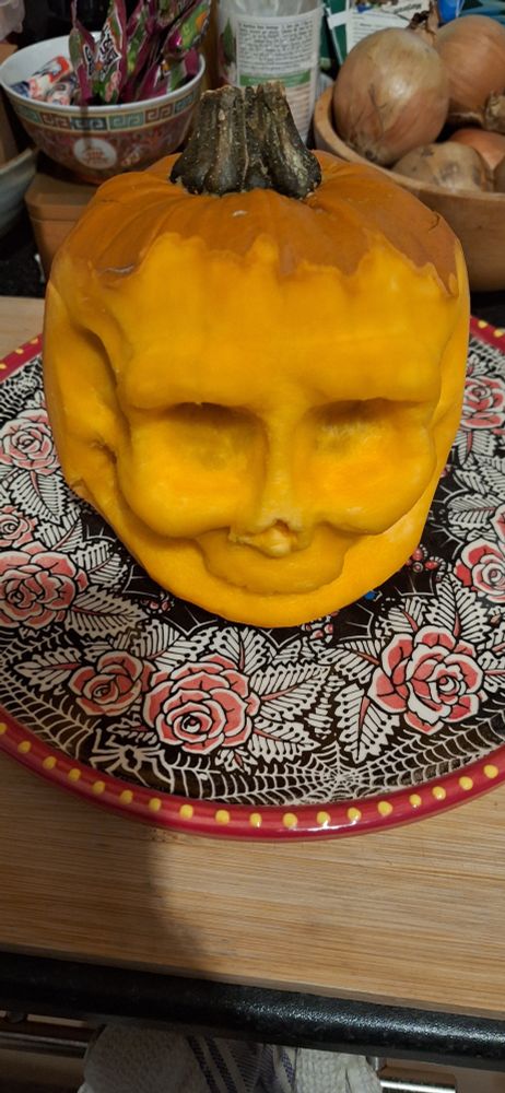 A very orange pumpkin carved into a skull shape at the front