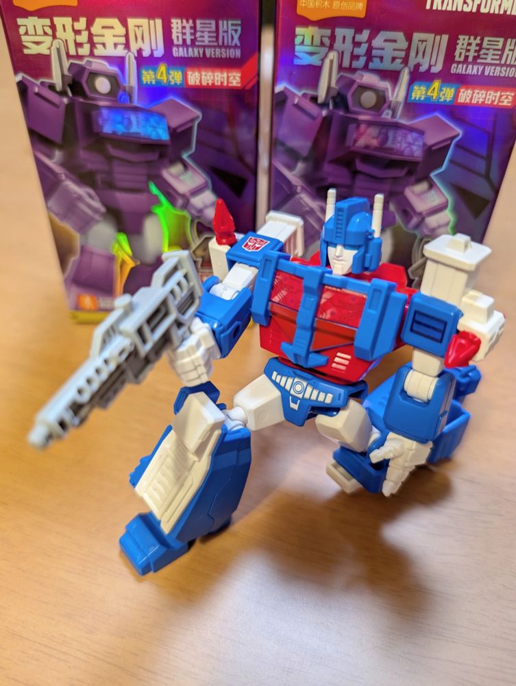 トランスフォーマーのキャラクター、ウルトラマグナスの約10cmほどのフィギュア
膝をつき、右手に持ったライフル型の銃を構えるようにポージングしている
背景には変形金剛と書かれたフィギュアの空箱が2つ並べられている